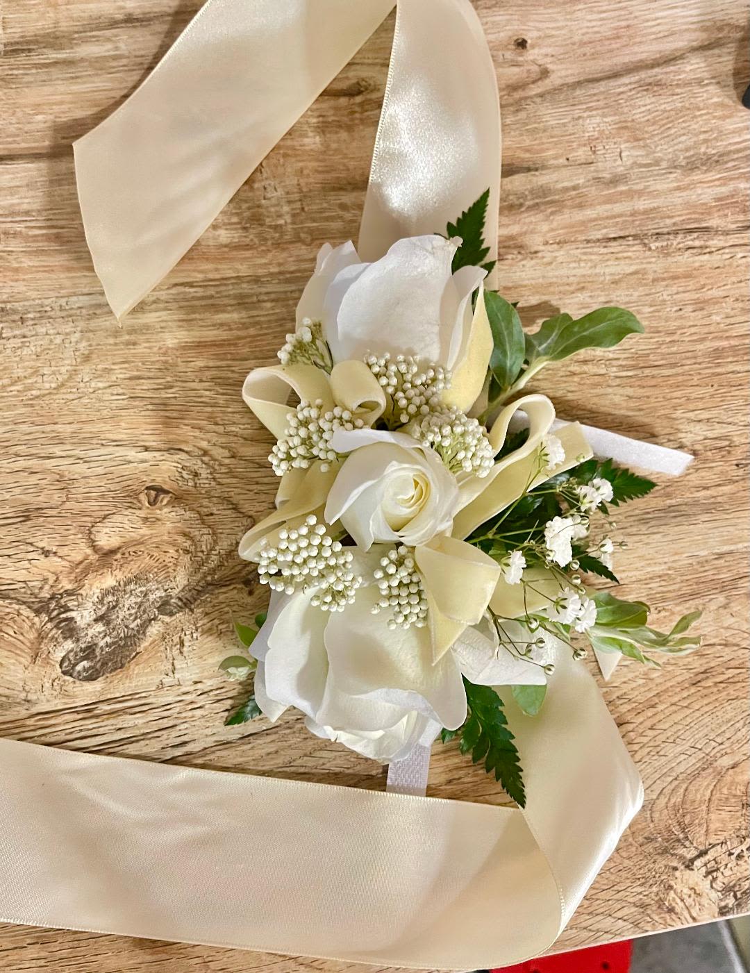 White rose corsage with cream ribbon and small white filler flowers