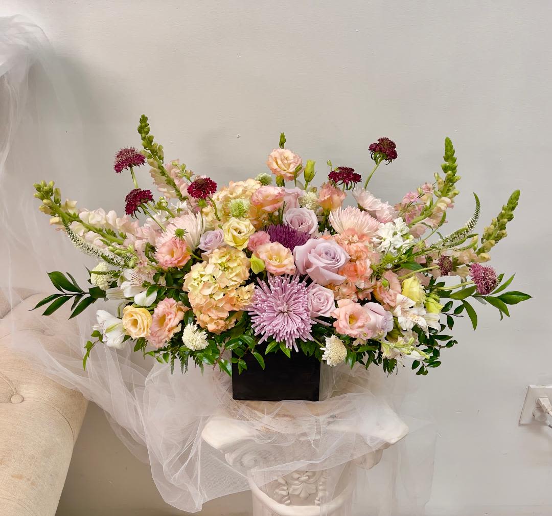 Large pastel floral arrangement in a black rectangular container