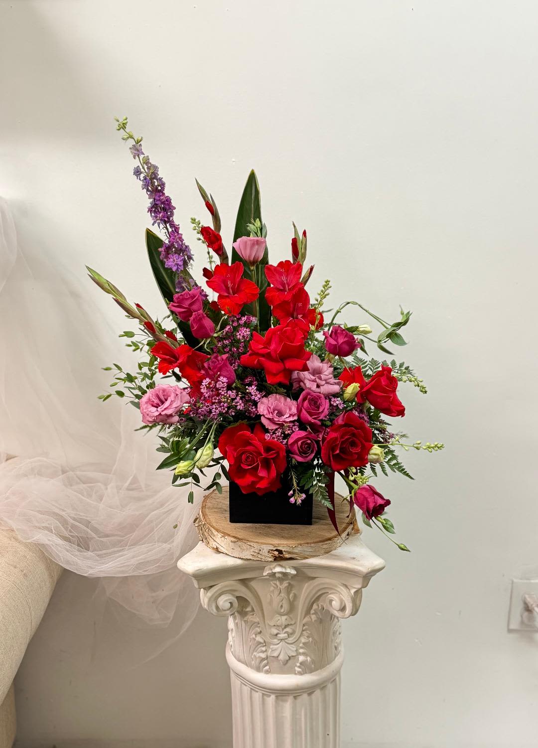 Tall arrangement of red and pink flowers in a black container