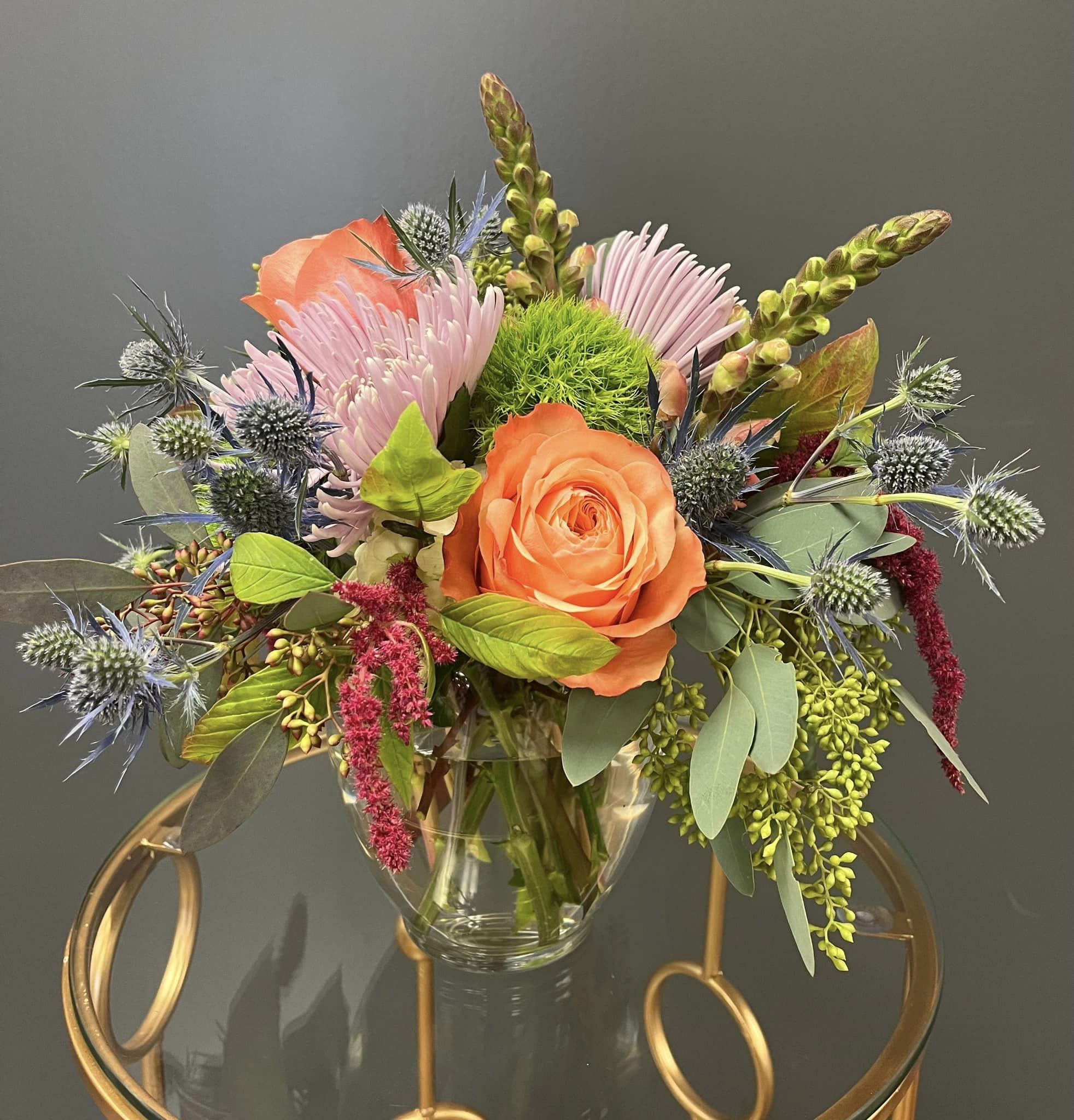 Orange rose and pink blooms in a clear glass vase