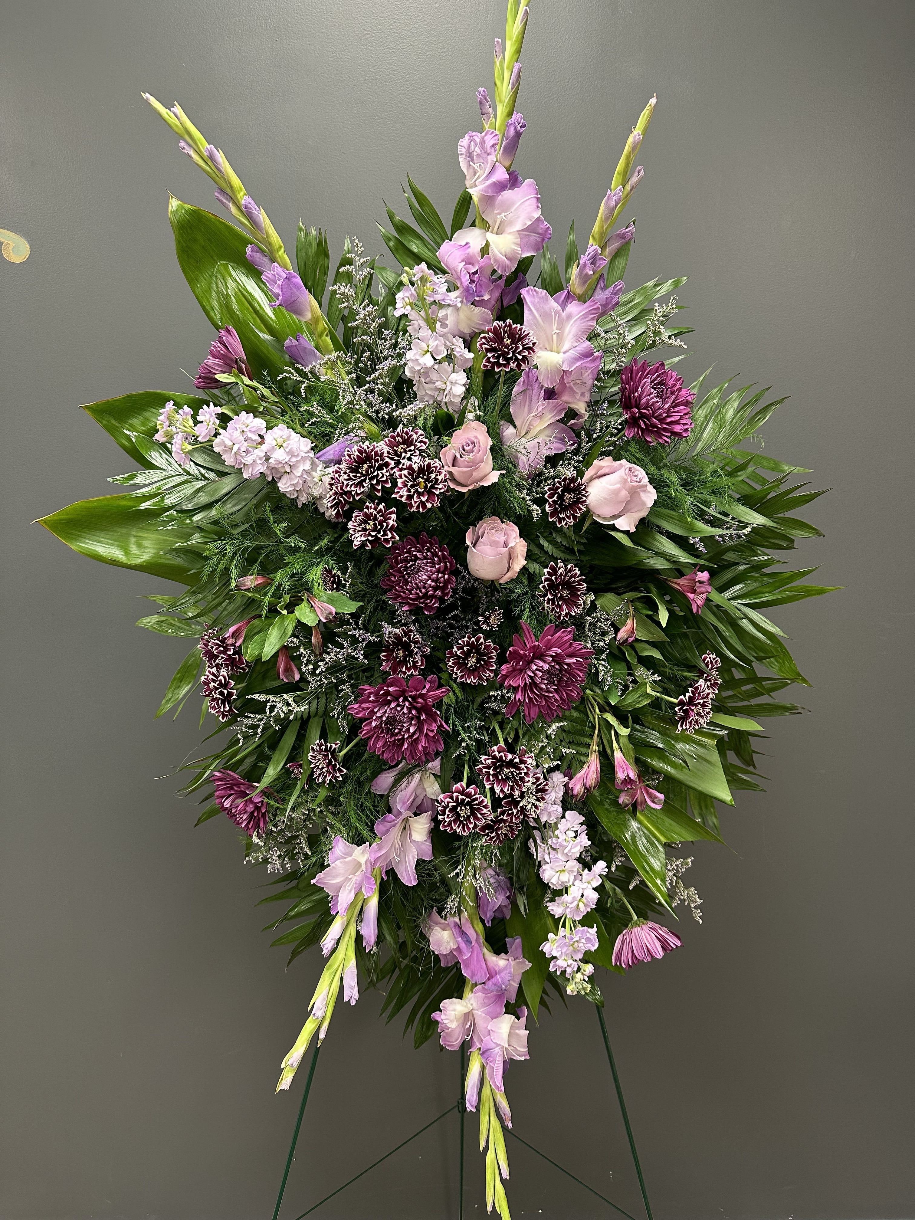 Standing floral spray with pink and purple flowers on a wire easel