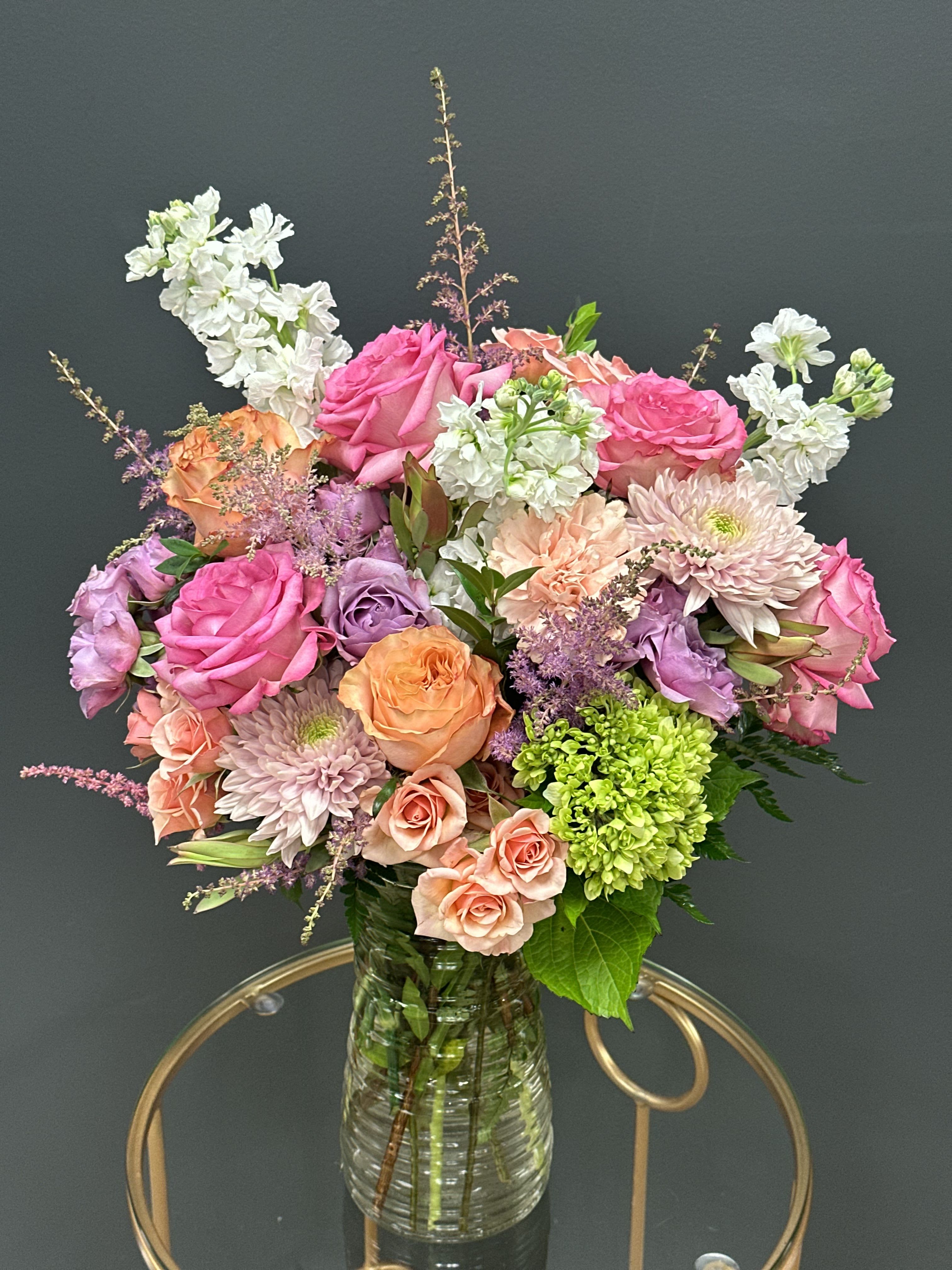Mixed pink, peach, and white flowers in a clear glass vase