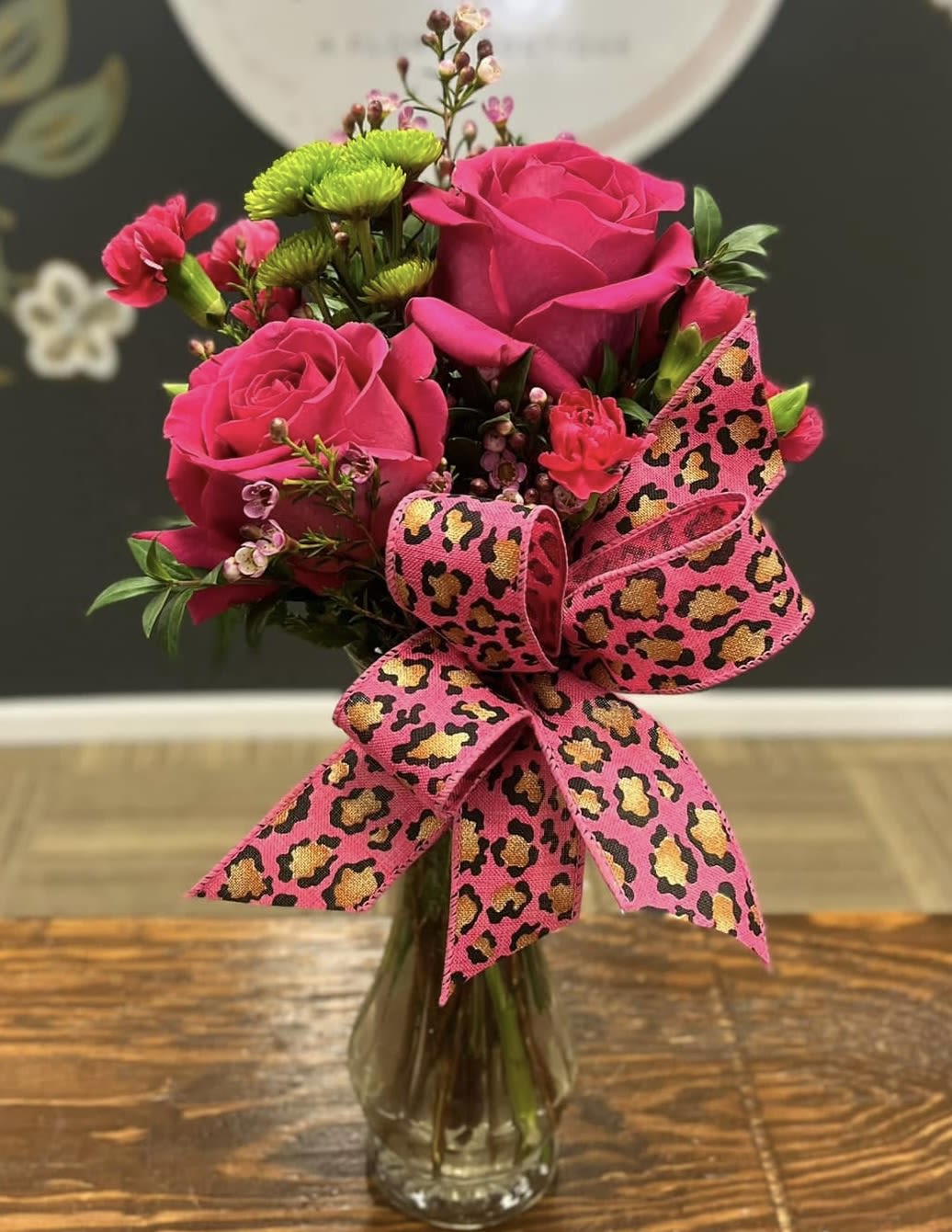 Pink rose bouquet in a glass vase with a leopard-print ribbon