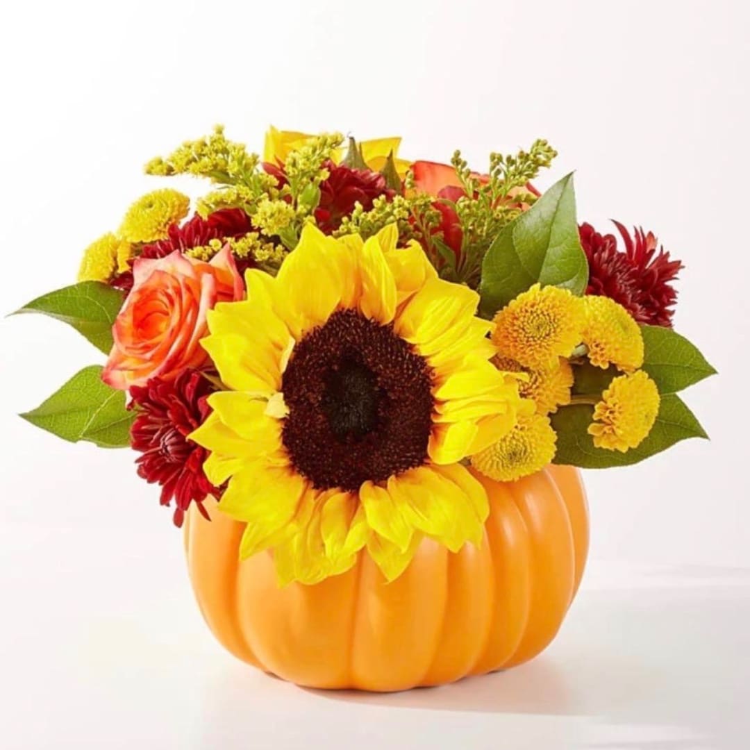 Sunflower and mixed autumn flowers arranged in a pumpkin container