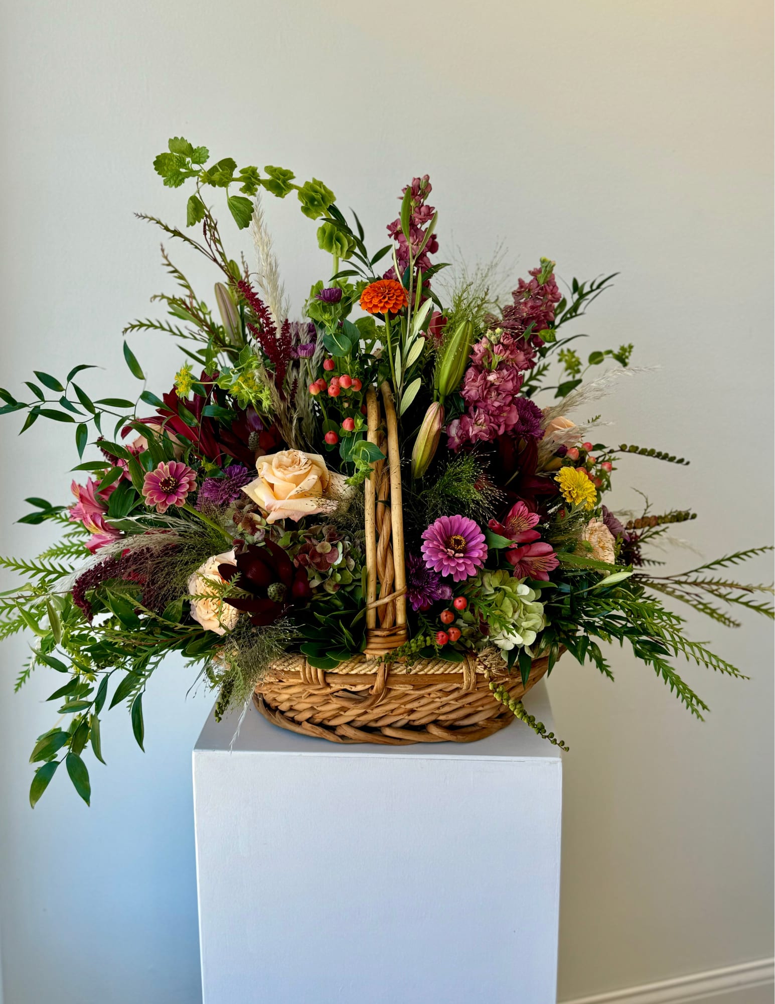 Mixed flower arrangement in a wicker basket with pink, purple, and peach blooms