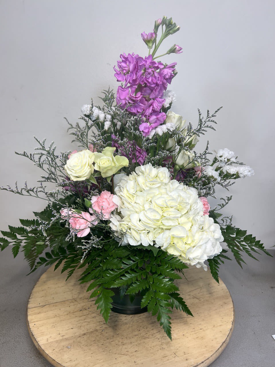 Tall floral arrangement with white and pink blooms in a dark vase