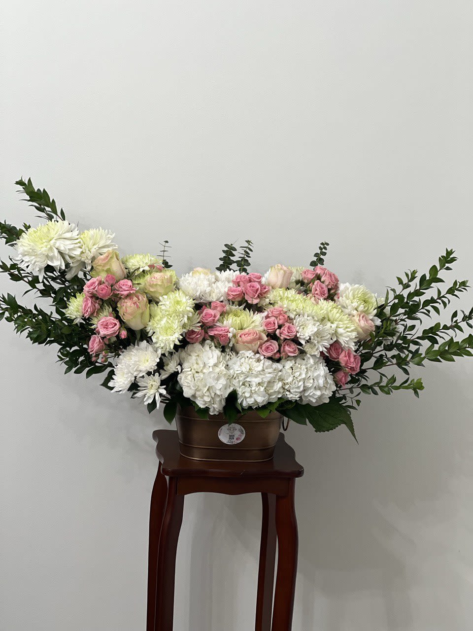 Large white and pink floral arrangement in a brown container on a stand