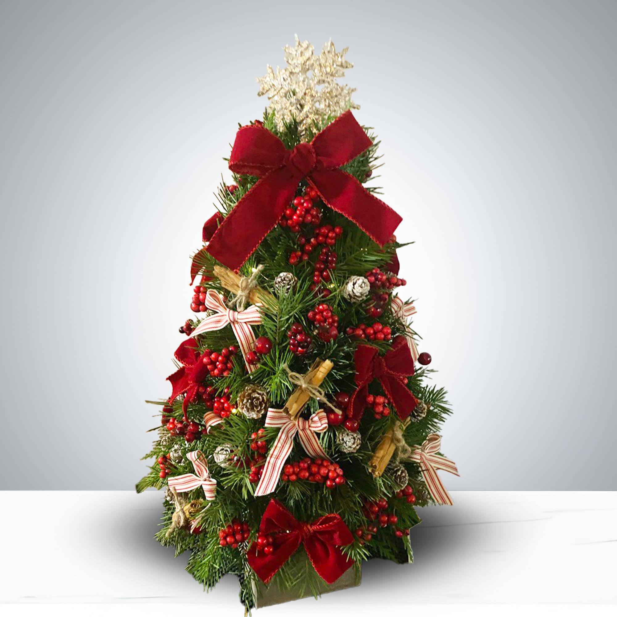 Luxury Mini Tree by GIA - Elevate your seasonal style with the Luxury Mini Tree by GIA, a handcrafted Christmas centerpiece designed to bring festive charm to any space. This petite yet opulent tree features: - Rich red velvet bows and striped ribbon accents for a classic holiday touch - Clusters of realistic red berries and natural pinecones for botanical authenticity - A shimmering spray of silver-white foliage crowning the top for a luxe finish - Perfectly sized for desks, mantels, entryways, or gift-giving 