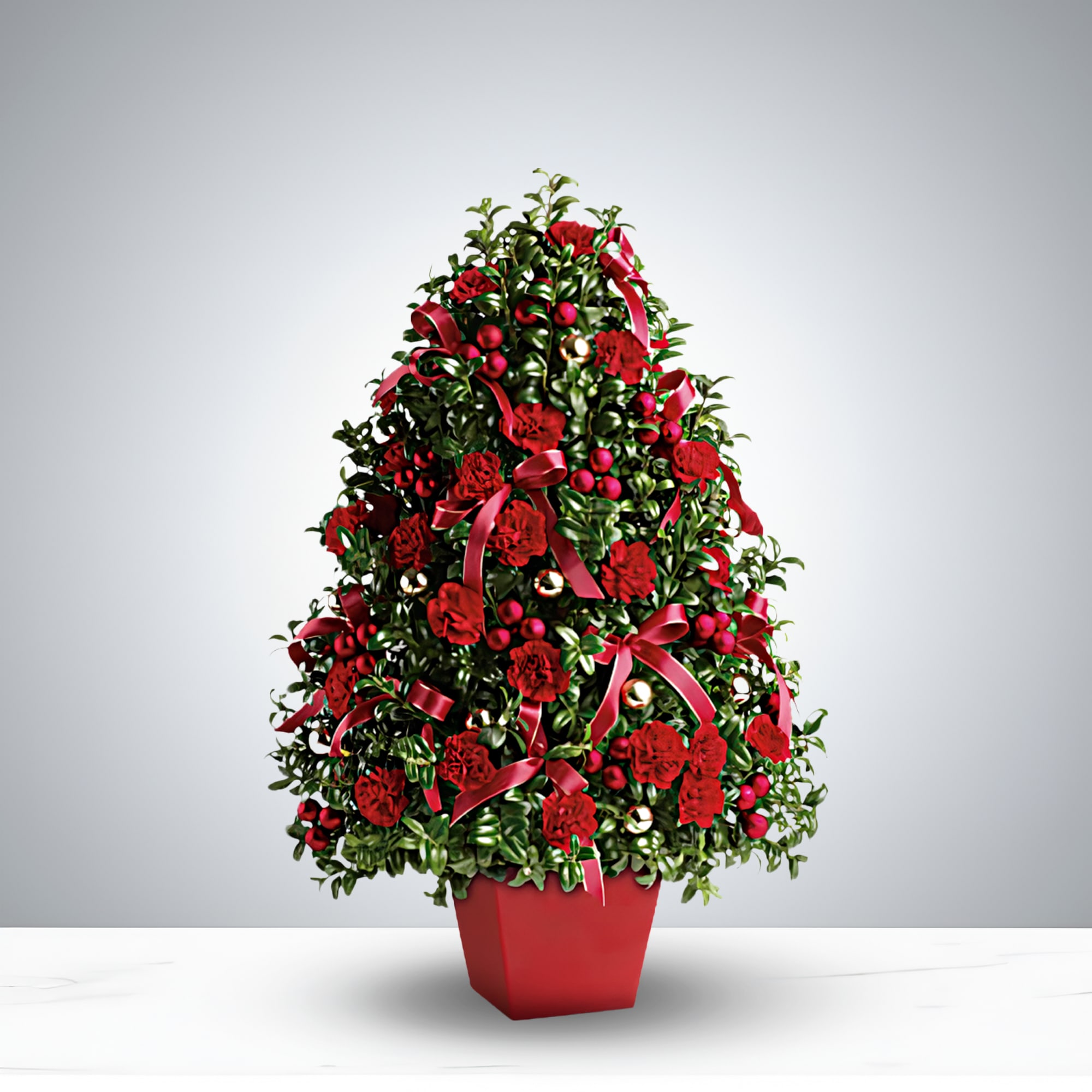 Heart of Christmas - Brighten your holidays with the Heart of Christmas, a handcrafted Christmas floral arrangement full of seasonal charm. Lush evergreen foliage, vibrant red flowers, sparkling ornaments, and cheerful berries are accented by elegant crimson ribbons. Presented in a bold red pot, this holiday centerpiece is perfect for home décor, office displays, or as a thoughtful Christmas gift. Celebrate the season with a radiant festive decoration that’s merry, bright, and unforgettable.