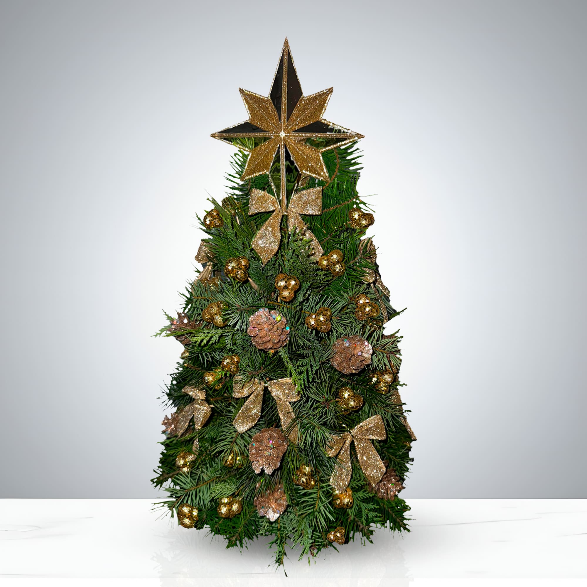 Royal Gold Tree by GIA - Elevate your holiday décor with the Royal Gold Tree, a premium artificial Christmas tree designed to dazzle. This lush, symmetrical evergreen is richly adorned with gold ornaments, including shimmering bows, elegant baubles, and festive pinecones. Topped with a glittery gold-and-black star and matching bow, it brings regal charm to any space. Perfect for living rooms, storefronts, holiday events, or Christmas photo backdrops, the Royal Gold Tree blends timeless tradition with upscale style. Its dense branches offer a full, natural look—ideal for showcasing your favorite decorations.