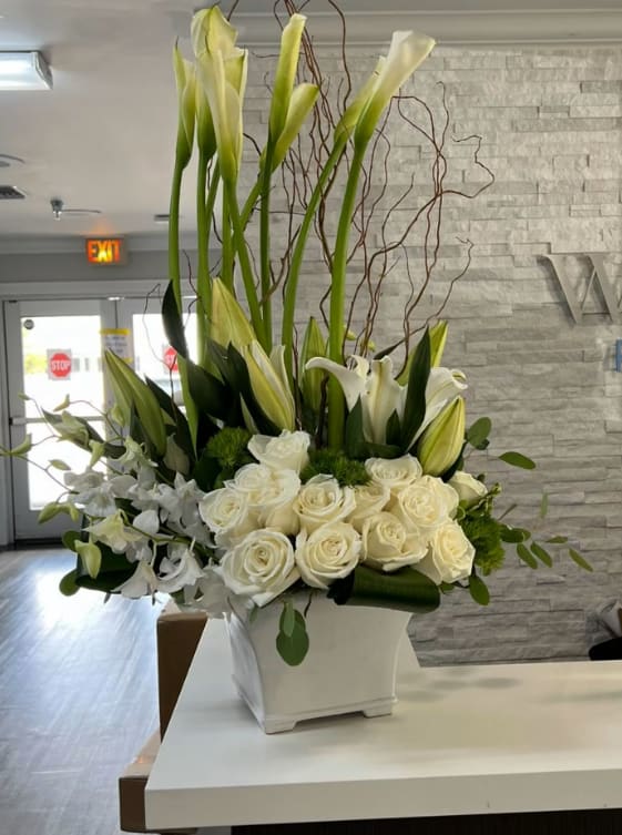 White Stems - One of the best seller arrangement in whites Calla lilies, orchids, roses, snaps and more of the freshest flowers in a white ceramic container 