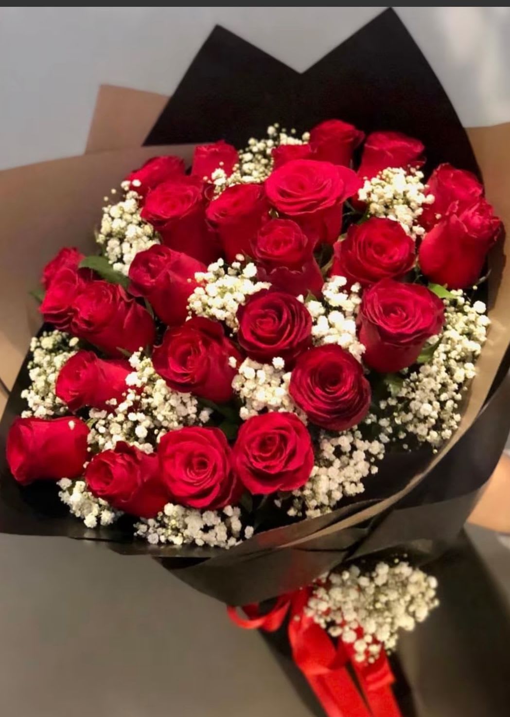 Bouquet of red roses with white baby's breath in black wrapping