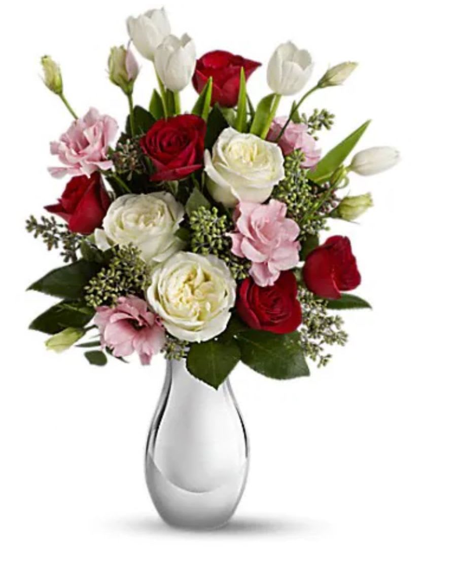 Bouquet of red and white roses with pink blooms in a clear glass vase