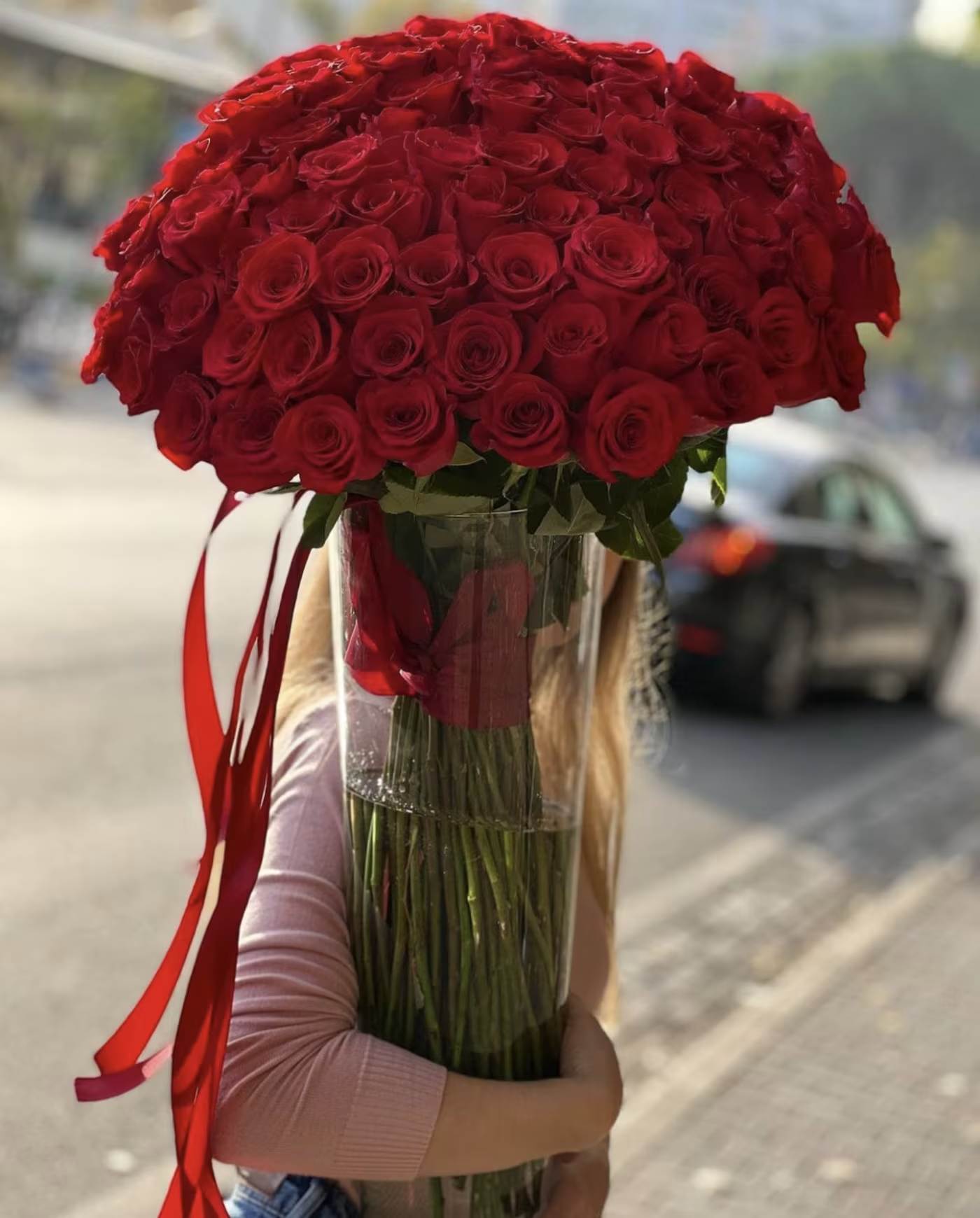 Large bouquet of red roses in a clear vase with red ribbon