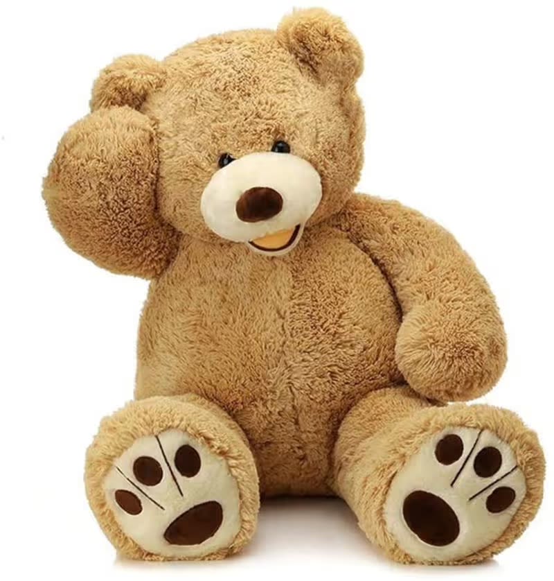 Teddy Bear 50" - A cuddly seated teddy bear plush makes a heartfelt gift for a new baby, birthday, or just-because surprise - this 50" teddy bear is warm tan and brown with oversized paws and a simple, friendly face that reads as playful and affectionate. As a gift item rather than a traditional floral arrangement, it sends an unmistakable message of comfort and warmth that will make the person you're thinking of feel cozy and cared for.  The plush bear features soft fuzzy fur in brown and tan tones with subtle white and black accents in the face for gentle contrast; it sits upright with one paw lifted near its head for an endearing, childlike pose. Perfect for nurseries, bedside cuddles, or a comforting bedside companion for someone recovering, this large plush arrives ready to hug - no special care needed beyond spot cleaning - and ships in protective packaging to ensure it reaches your recipient in snuggly condition.