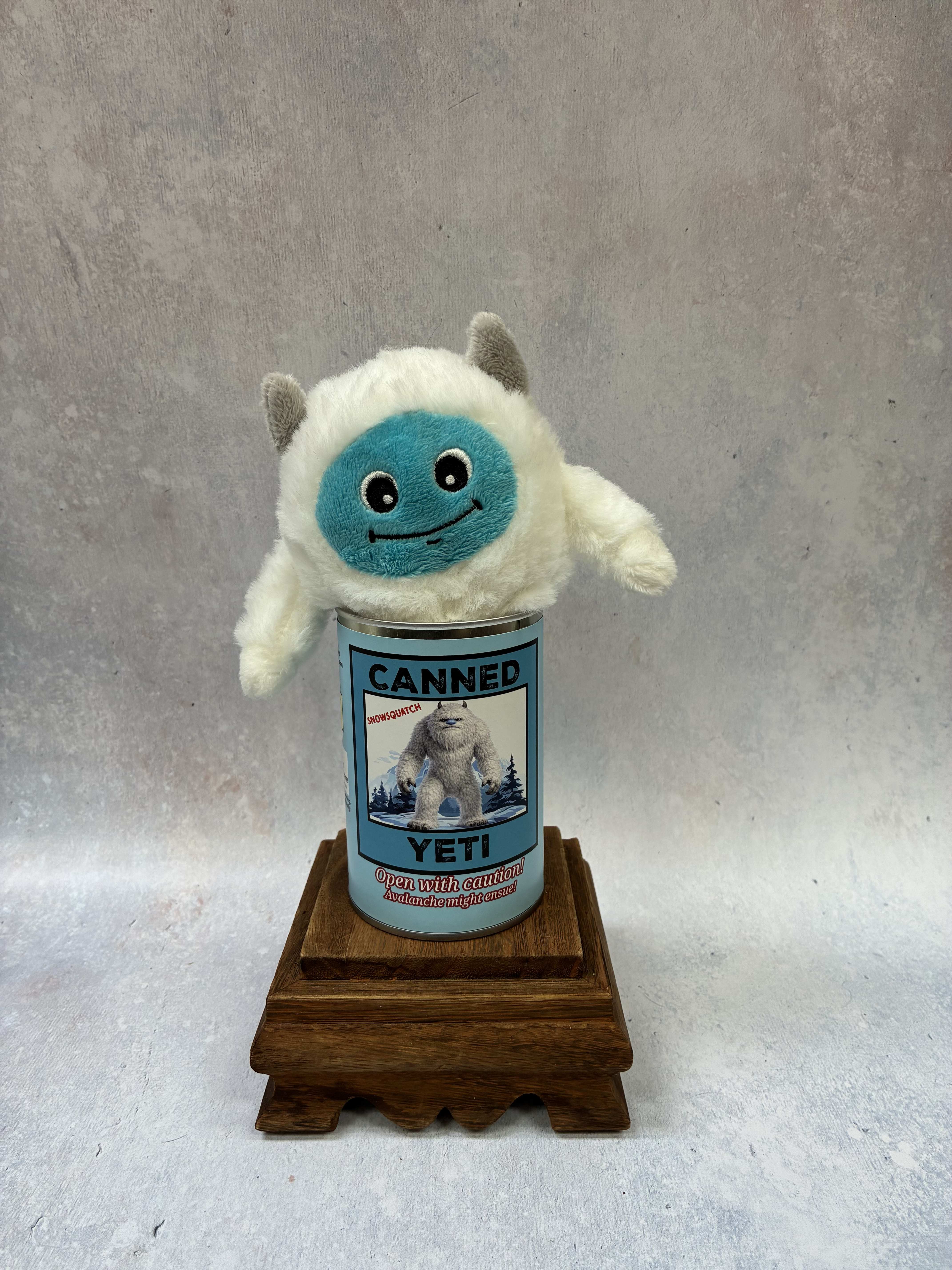 Plush yeti toy sitting in a labeled can on a wooden stand