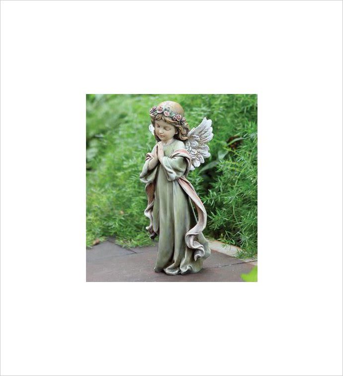 Garden angel statue of a praying child with wings and a flower crown on a stone path