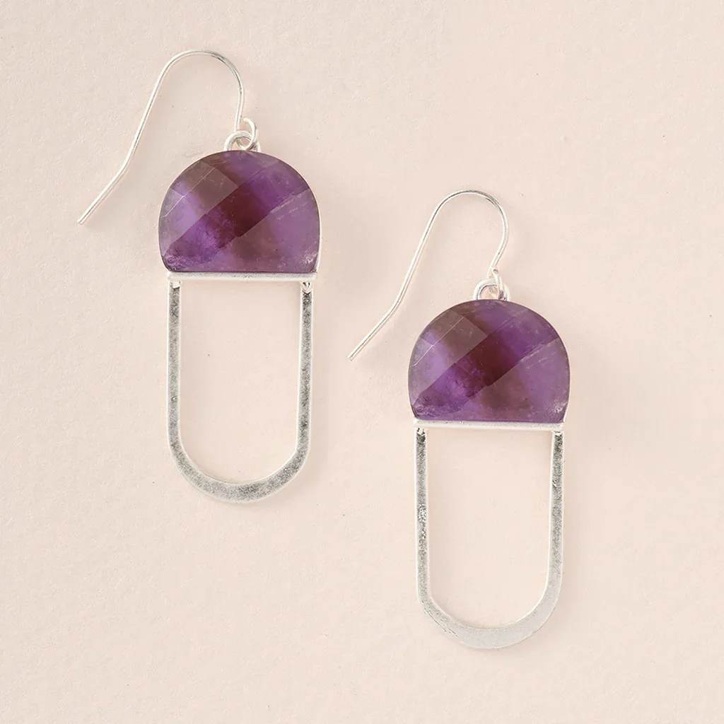 Pair of silver drop earrings with faceted purple semicircle stones on a light background