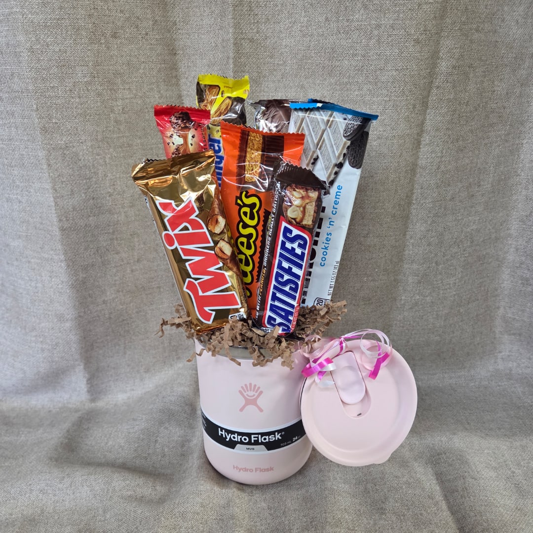 Pink Hydro Flask mug filled with assorted candy bars and a ribboned lid beside it