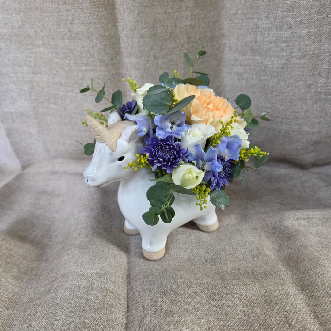 Flower arrangement in a white unicorn vase with purple, white, and peach blooms