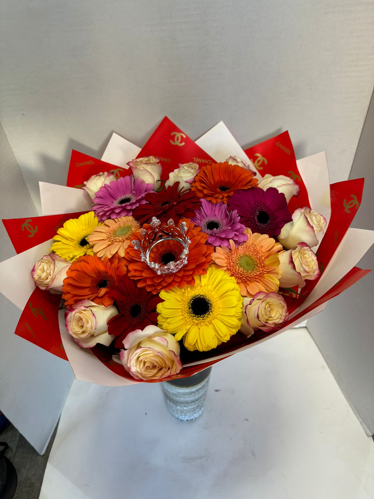 Colorful bouquet of gerbera daisies and roses wrapped in red and white paper