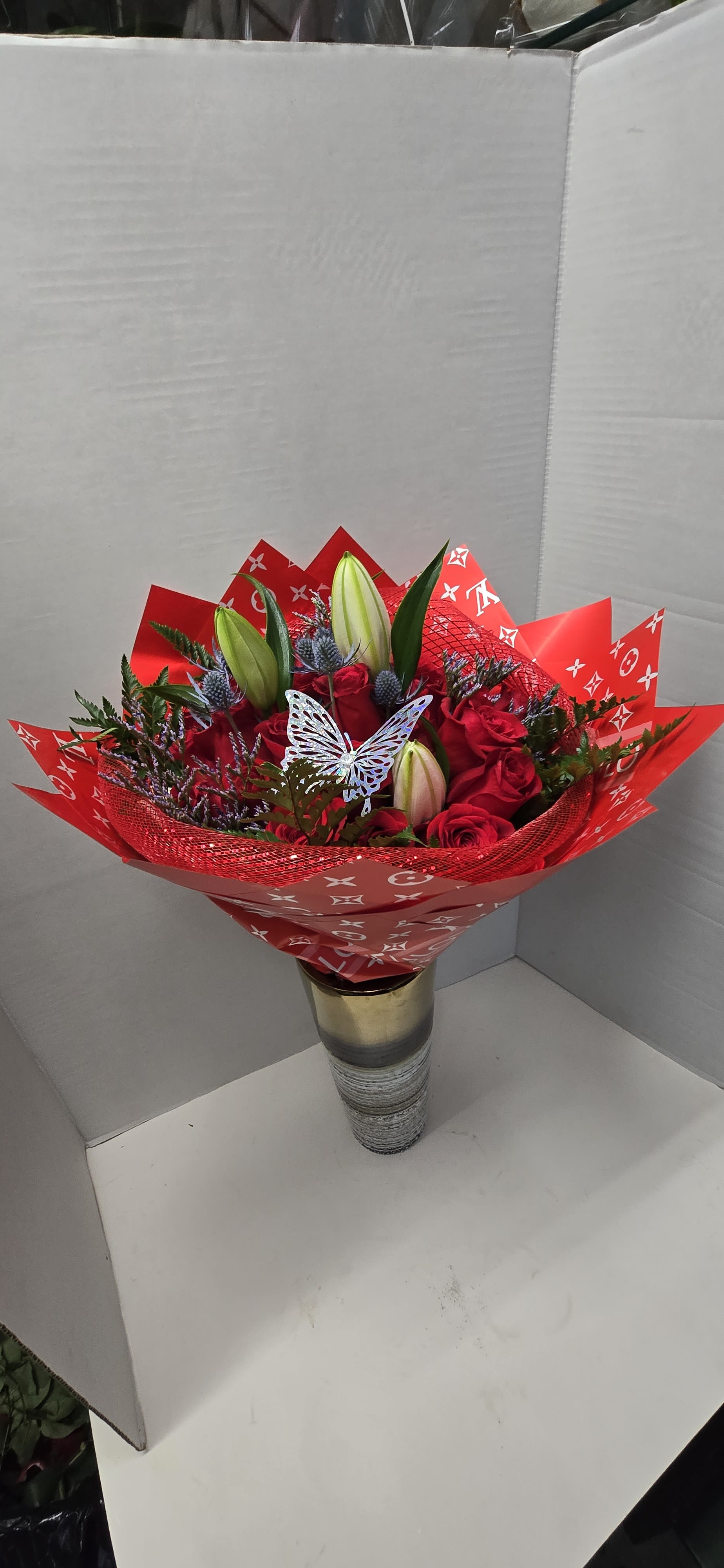 Red rose bouquet with lily buds in a gold vase