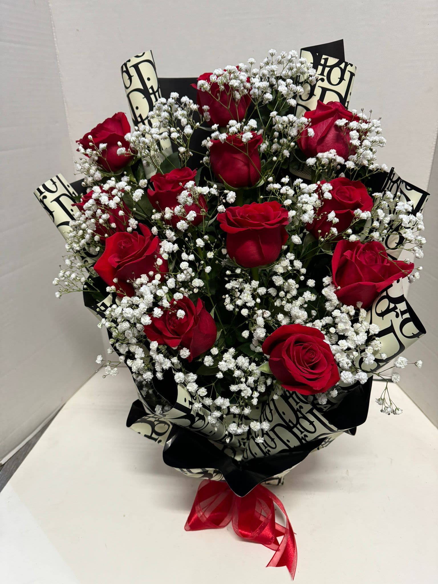 Bouquet of red roses with white baby's breath and black patterned wrap