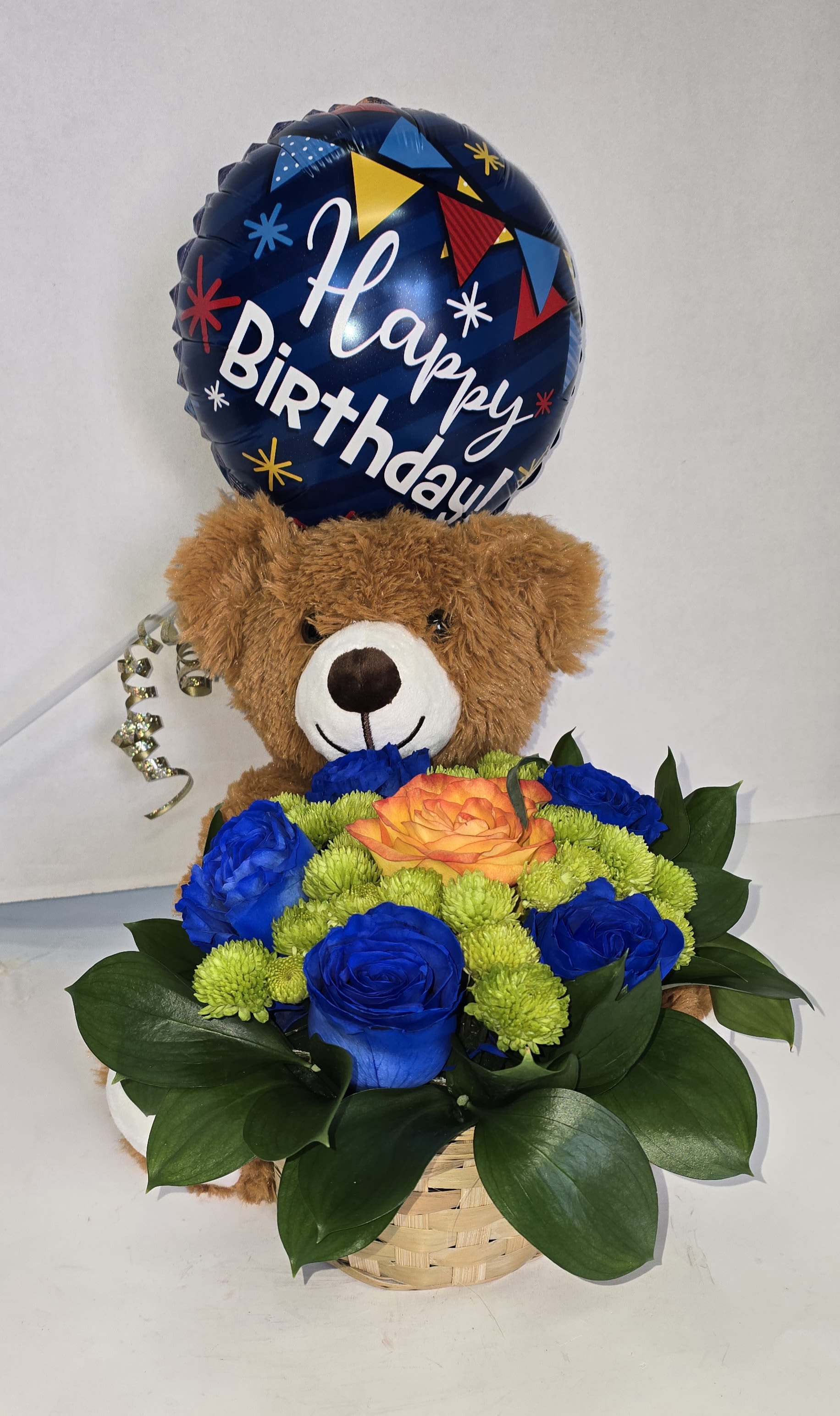 Birthday balloon above a teddy bear holding a basket of blue and orange flowers
