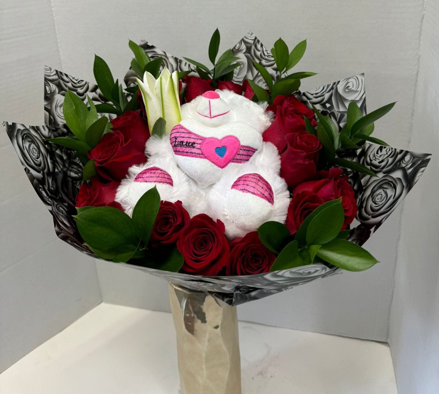 Bouquet of red roses with a white teddy bear in the center