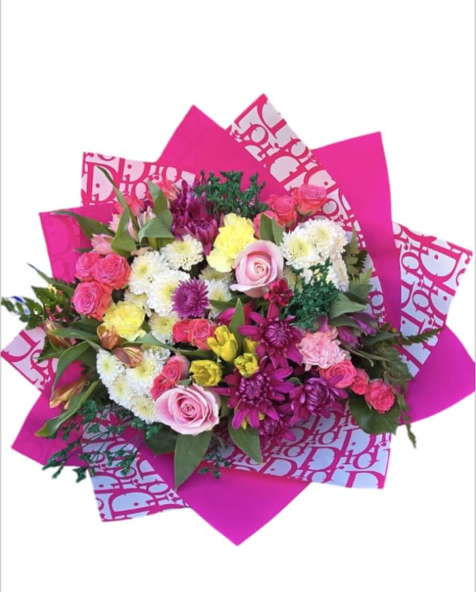 Bright mixed bouquet with pink, white, and yellow flowers wrapped in hot pink paper