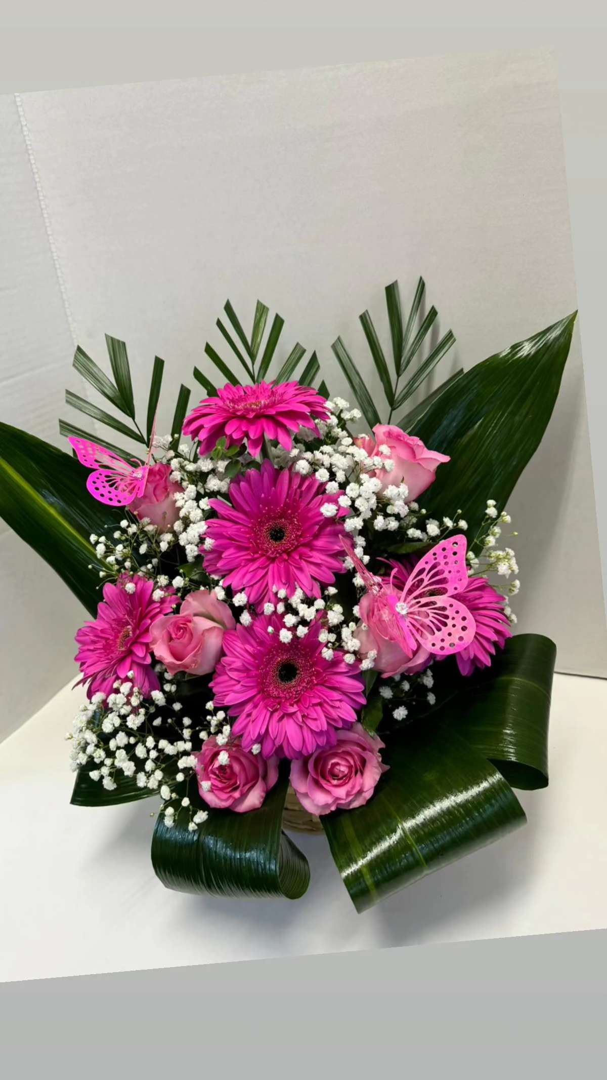 Pink gerbera and roses arranged with white baby's breath