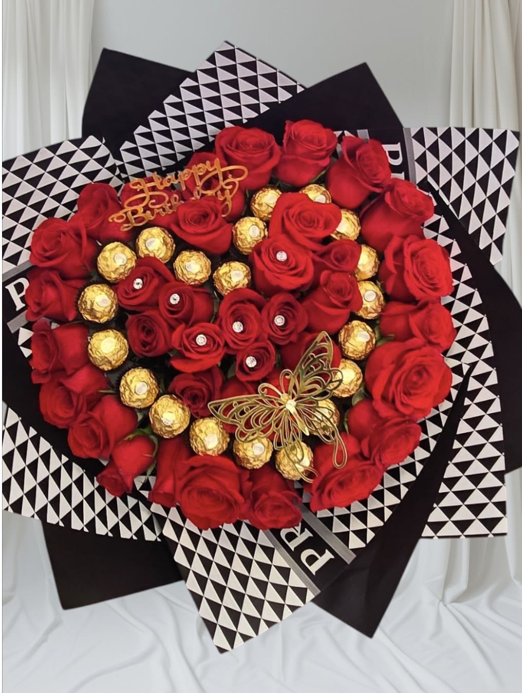 Heart-shaped bouquet of red roses and gold-wrapped chocolates