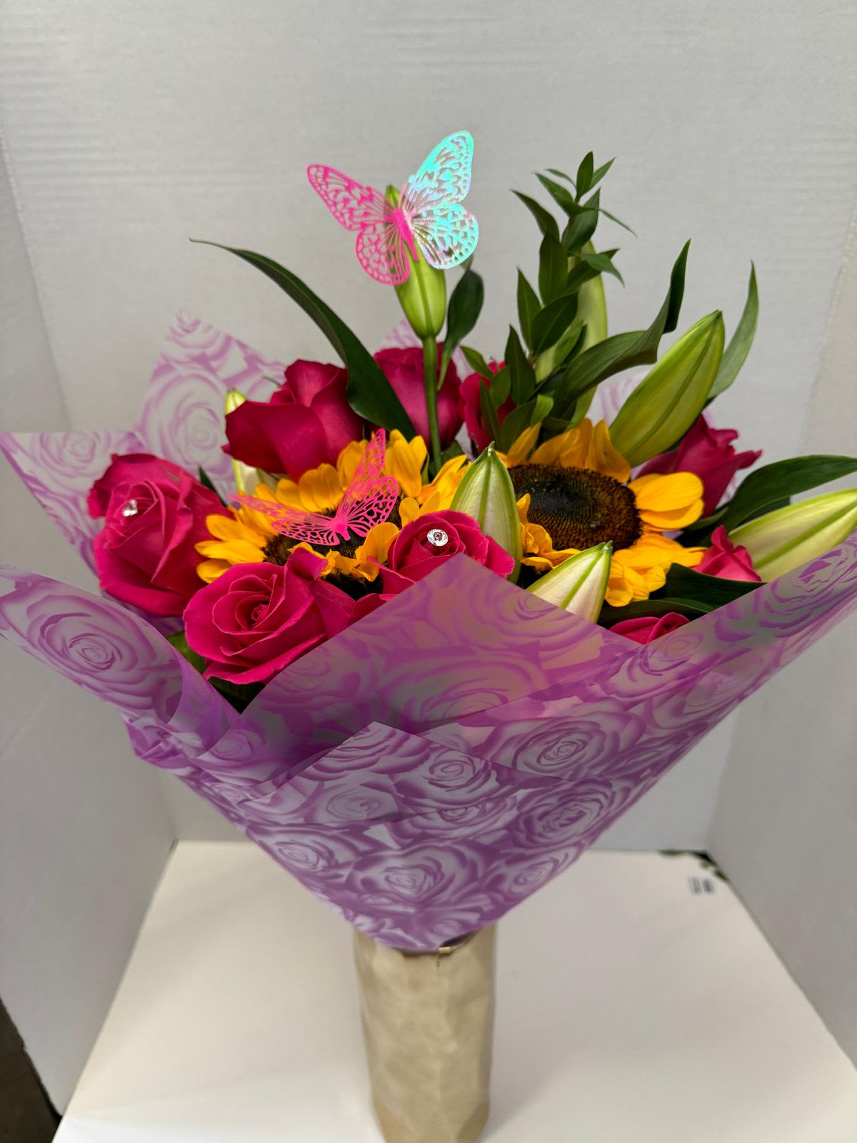 Bouquet of pink roses and yellow sunflowers wrapped in purple paper