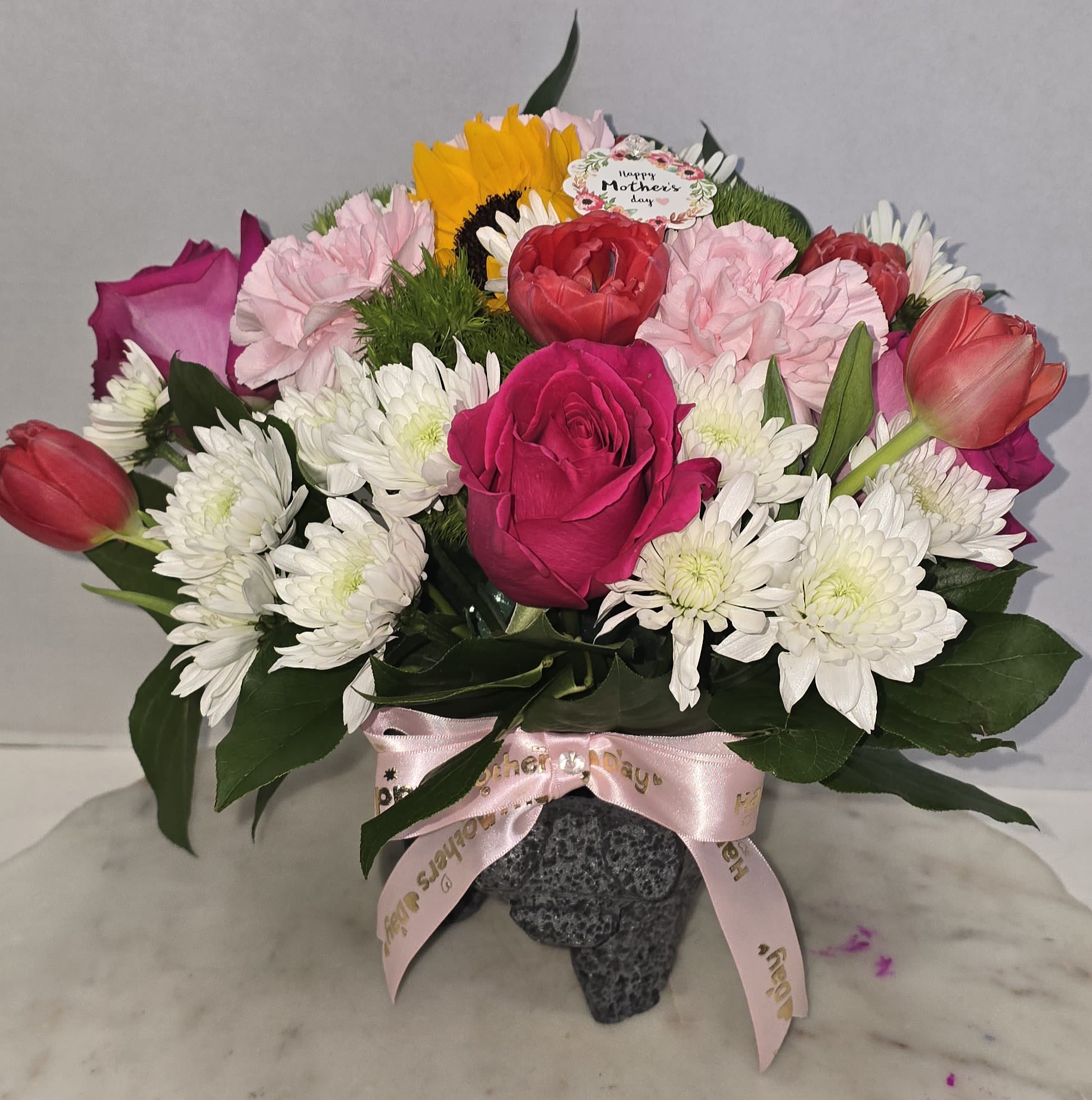 Mixed bouquet of roses, tulips, carnations, and white daisies in a vase