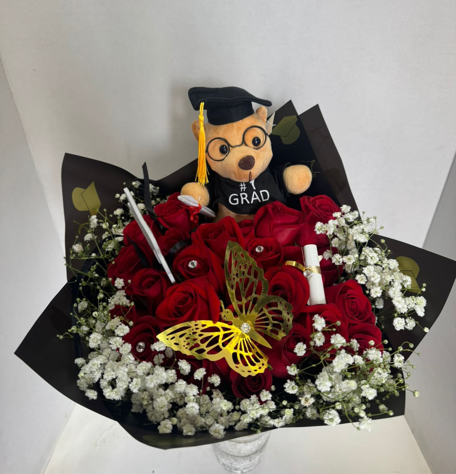 Red rose bouquet with baby’s breath and a graduation teddy bear topper