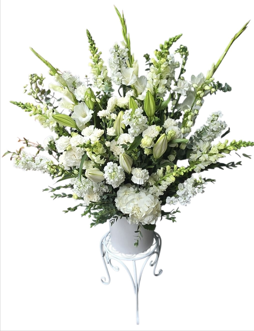 White floral arrangement in a white vase on a metal stand