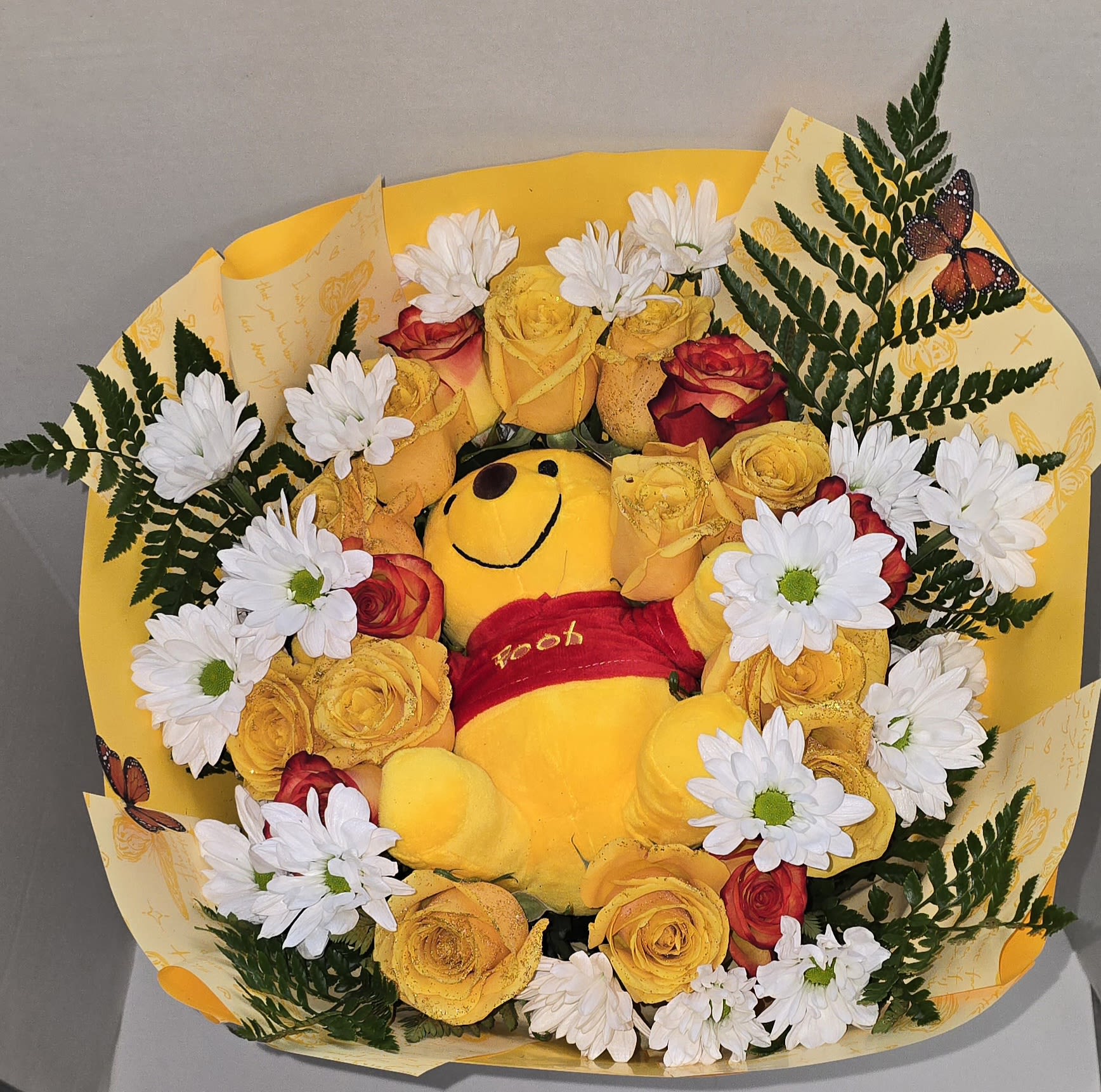 Bouquet with a Winnie the Pooh plush surrounded by yellow roses and white daisies