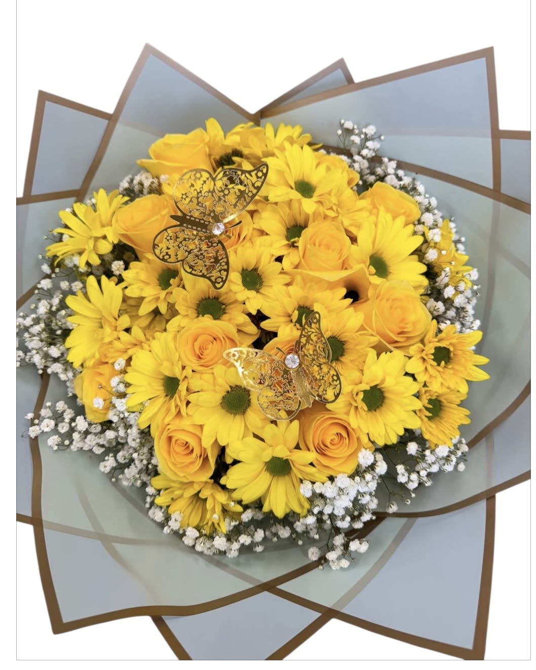 Yellow daisies and roses in a wrapped bouquet with butterfly picks
