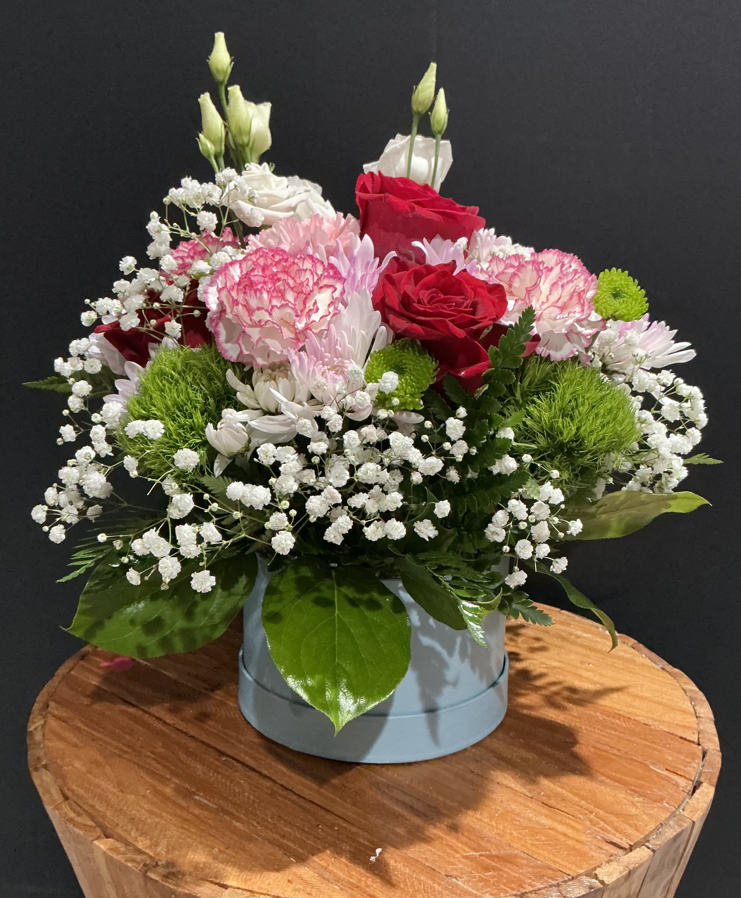 Mixed bouquet of red and pink roses with white filler flowers in a round box
