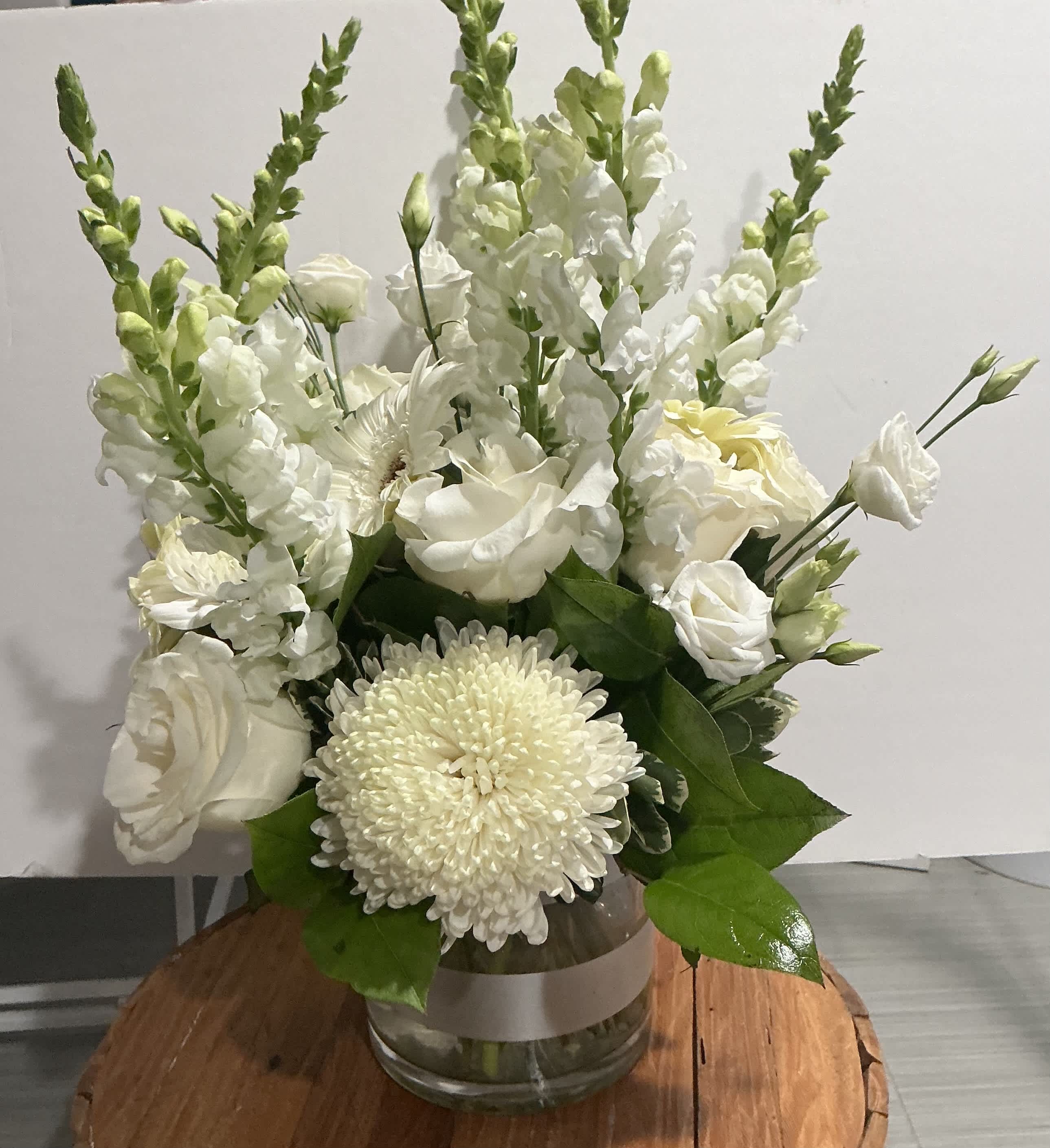 White floral arrangement in a glass vase with tall snapdragons and chrysanthemums
