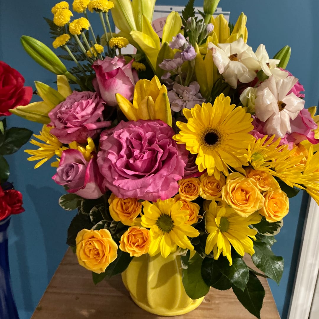 Mixed bouquet of pink, yellow, and white flowers in a yellow vase
