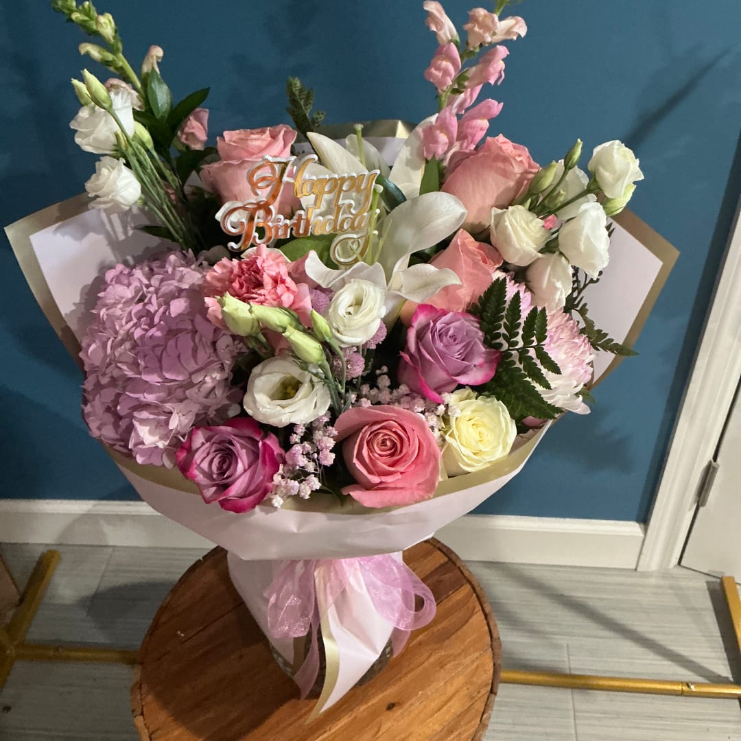 Pink and white mixed flower bouquet with a birthday topper