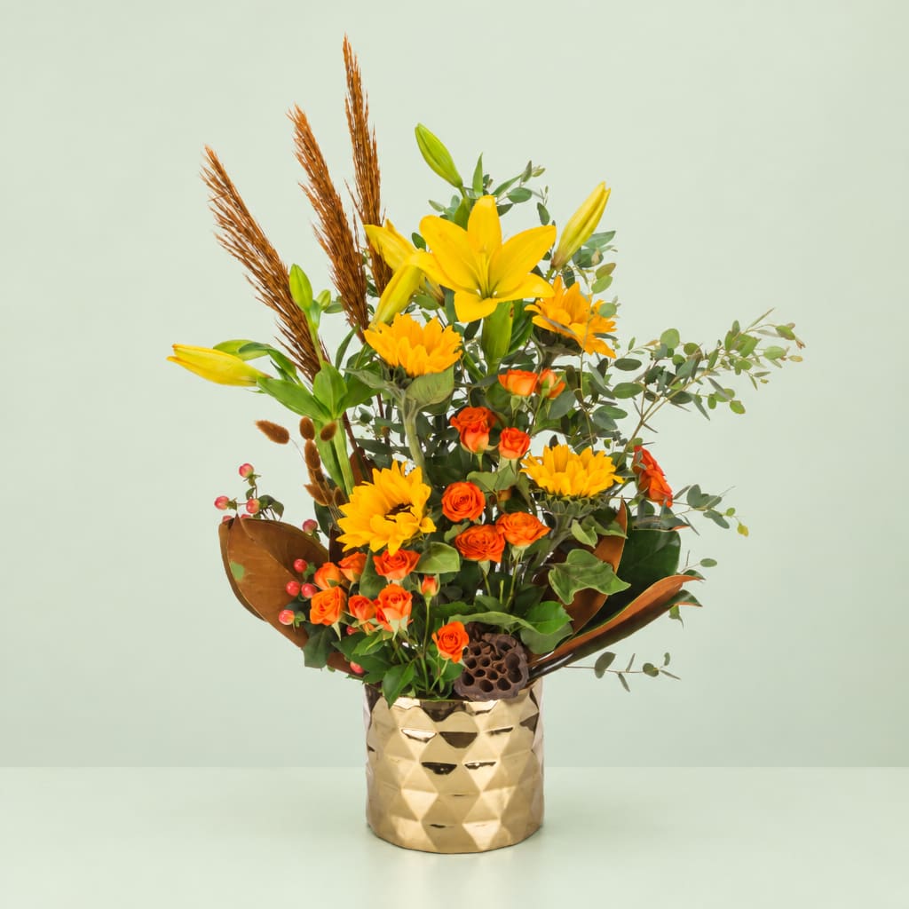 Yellow lilies and orange roses in a gold vase