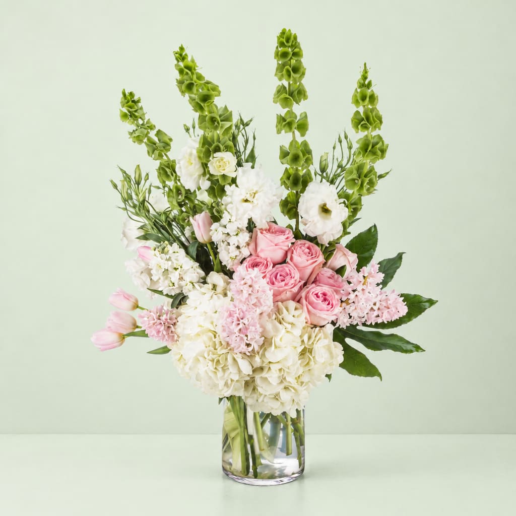 Pink and white bouquet in a clear glass vase with tall green spikes