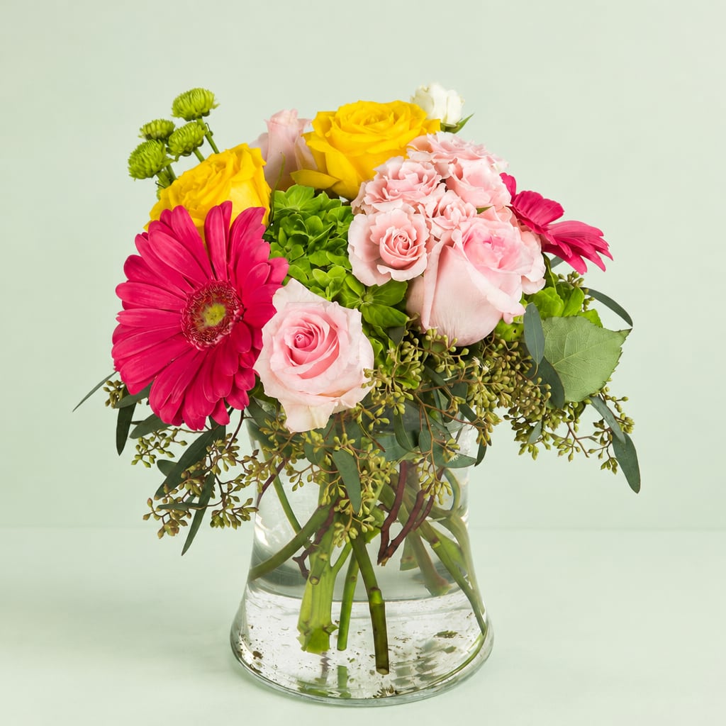 Mixed bouquet of pink and yellow flowers in a clear glass vase