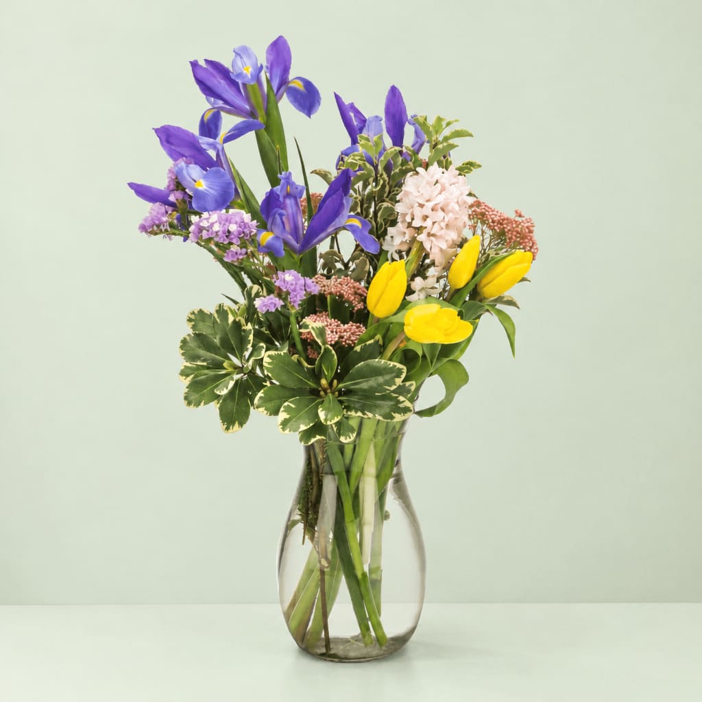 Mixed bouquet of purple irises and yellow tulips in a clear glass vase