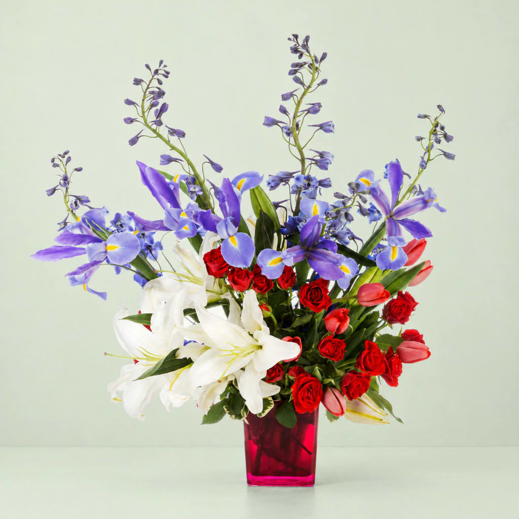 Bouquet of red roses, white lilies, and purple irises in a pink glass vase