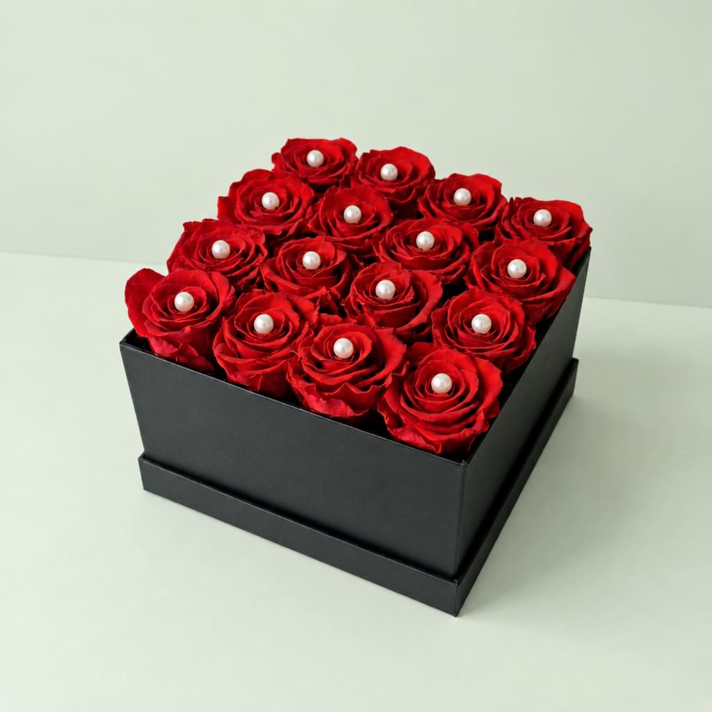 Red roses arranged in a black square box with pearl accents