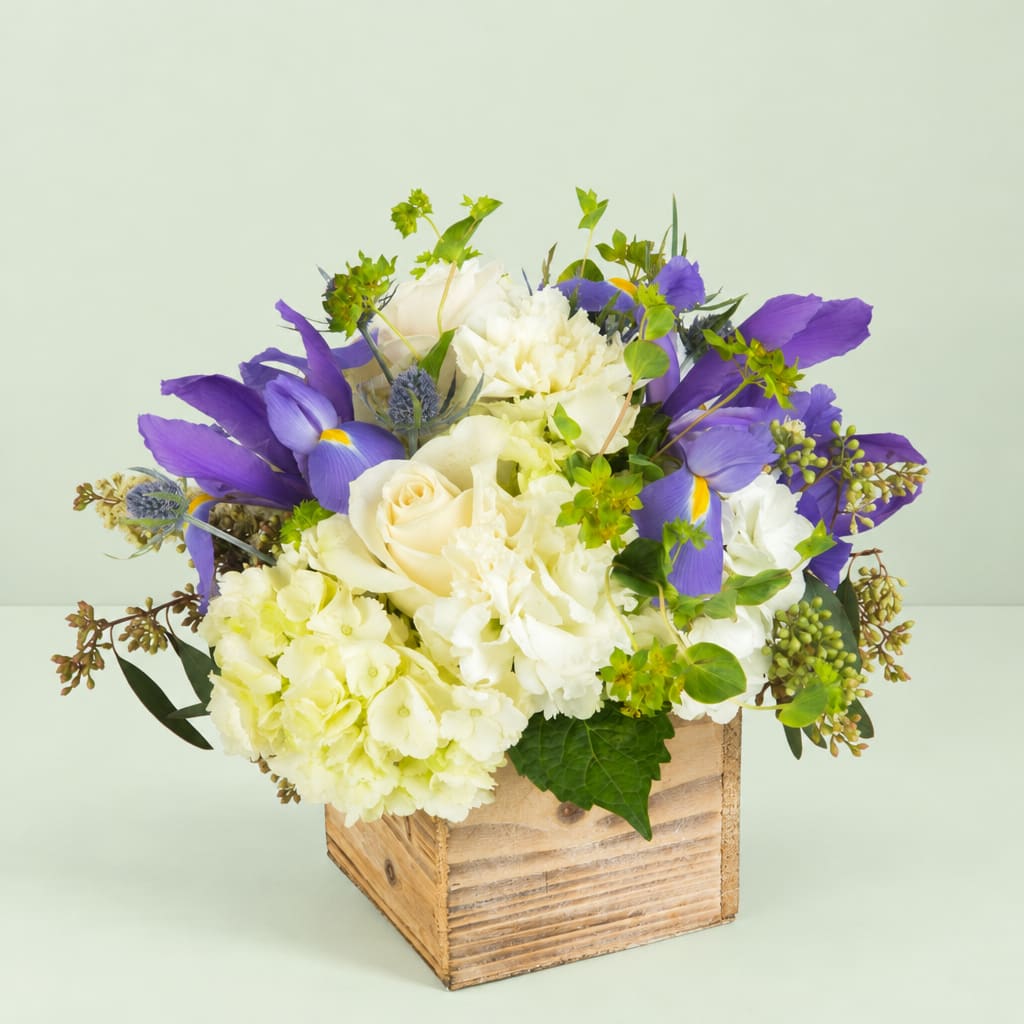 Purple and white floral arrangement in a wooden box