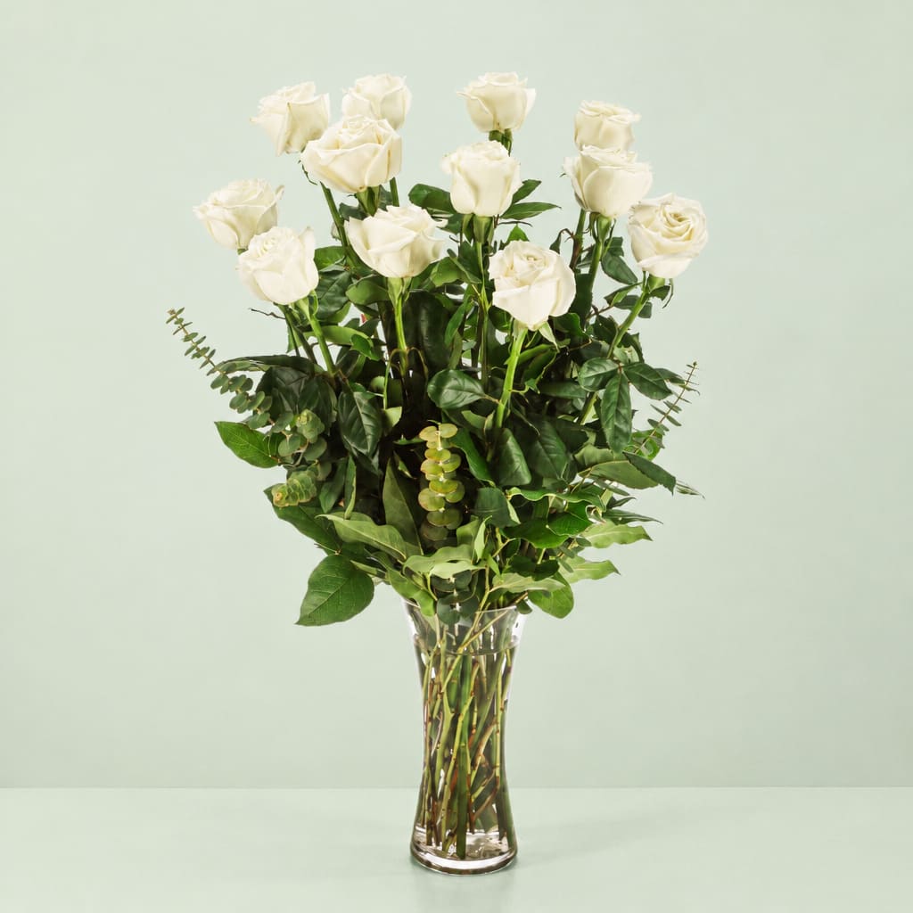 Tall vase arrangement of white roses with greenery